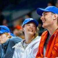 Side view of 3 people smiling in the stands of Comerica Park